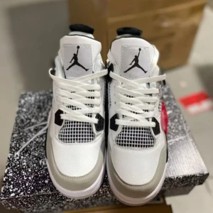 Nike Air Jordan 4 Military Black - Nike Air Jordan 4 sneakers i vitt, svart och grått med klassisk Jumpman-logga på plösen och hälen. Ovandel i skinn och mesh, coola detaljer med svarta plastpaneler och snörning. Snygg och sportig siluett som sticker ut.