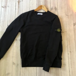 Svart tröja från Stone Island - Säljer en stilren svart tröja från Stone Island med deras ikoniska märke på ärmen. Tröjan har långa ärmar och en klassisk rund halsringning. Perfekt för en avslappnad och trendig look. Bara att skriva om du vill ha bild på certlilogo eller om du har andra frågor!