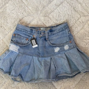 Kort jeanskjol med volang - Snygg jeanskjol från Levis med volang längst ner. Den är kort i modellen och är köpt på en marknad i Thailand men den passade inte så den är helt oanvänd och ny. 