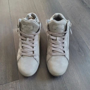 Grå vårskor från  Alley - Snygga grå sneakers från Alley med snörning och dragkedja på sidan för enkel på- och avtagning. Skorna har en stilren design med perforerade detaljer och en bekväm passform. 