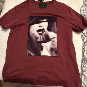 Vinröd t-shirt med tryck från Limitato - Säljer en vinröd t-shirt från Limitato med ett coolt tryck av Ellen von Unwerth på framsidan. T-shirten är kortärmad och har en normal passform. Perfekt för dig som vill ha något unikt i garderoben!  Nypris 1800 