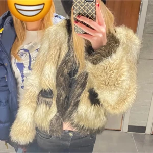 Beige och svart pälsjacka - Säljer en snygg beige och svart pälsjacka med långa ärmar. Jackan har en cool look, perfekt för att sticka ut i mängden. Den är varm och passar bra för kyligare dagar men även lite vårigare då den inte är för tjock. Köpt second hand.