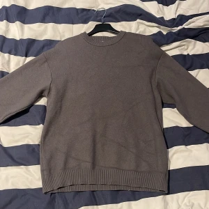 Grå tröja från Zara - Säljer en stilren grå tröja från Zara. Tröjan har en normal passform med ribbade muddar vid ärmslut och nederkant. Perfekt för en avslappnad look.