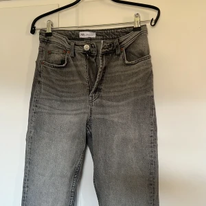 Grå jeans - Snygga grå jeans med hög midja och klassisk femficksdesign. Byxorna har en rak passform och stängs med dragkedja och knapp. Väldigt snygg tvätt på jeansen! 