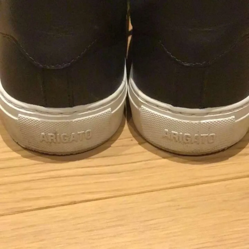 Snygga svarta sneakers från Axel Arigato med en broderad fågel i färgglada nyanser på sidan. Skorna har en vit sula och svarta snören, vilket ger en stilren look. Perfekta för en casual stil.. Kengät.