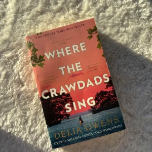 Where the Crawdads Sing - Boken 'Where the Crawdads Sing' av Delia Owens är en internationell bästsäljare. Den har en vacker omslagsdesign med en solnedgång över en sjö och träd i silhuett. Perfekt för dig som älskar spännande och gripande berättelser.