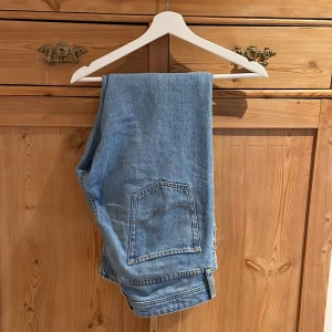 Blå jeansbyxor - Säljer ett par klassiska blå jeansbyxor med femficksdesign och knappgylf. De har en rak passform och är perfekta för en avslappnad stil. Midjemåttet är 31 och längden 32. Perfekta för vardagsbruk!