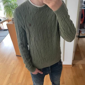 Olivgrön Ralph Lauren Tröja - Säljer en sjukt fet tröja från Ralph Lauren. Tröjan är kabelstickad och är i en olivgrön färg perfekt inför sommarn. Den är i strl m men kan även passa S. Hör gärna av er vid frågor elr funderingar!!