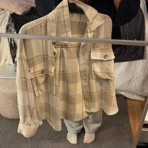 Beige rutig overshirt från Gina Tricot - Säljer en beige och ljusbrun rutig overshirt från Gina Tricot i storlek S. 