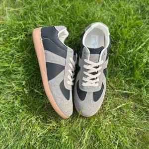 Grå och svarta sneakers med mockadetaljer - Snygga sneakers i grå mocka och svart syntet med beige snörning och ljusbrun gummisula. Skorna har en klassisk design med rund tå och platt sula, perfekta för en stilren vardagslook. Passar storlek 43-44. Cheap for a reason