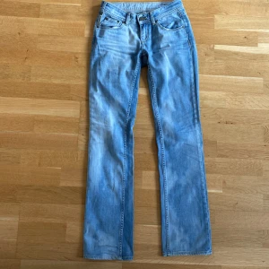 Ljusblå bootcut jeans - Säljer ett par ljusblå jeans med low waist och bootcut  passform och klassisk femficksdesign. Jeansen har normal passning och är tillverkade i denim med lätt tvättad look. Perfekta för dig som gillar en avslappnad stil.