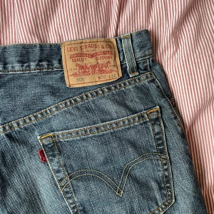 Levi's 501 blå jeans - Klassiska blå Levi's 501 jeans med raka ben och femficksmodell. Byxorna har normal passform och är tillverkade i slitstarkt denim med detaljerade sömmar och ikonisk läderpatch bak i midjan. Köpta seconhand, väldigt snygga!