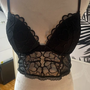  korsett-topp med hjärtmönster från intimissimi - Supersnygg svart korsett-topp med tunna axelband och spetsdetaljer. Toppen har hjärtmönster framtill. Lappen finns inte kvar men den är köpt på intimissimi. Passar nån som har S eller M och Strl 80 C. Skicka EJ prisförslag