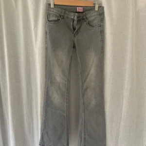 Grå bootcut jeans - Säljer ett par gråa jeans med bootcut passform, då de inte länge passar. Jeansen är lågmidjade och utan skavanker. Klassisk femficksmodell med knapp och dragkedja framtill. Jeansen har en något utsvängd benslut och är perfekta för en avslappnad passform. 