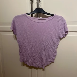 Ljuslila t-shirt från Size Needle - Säljer en ljuslila t-shirt från Size Needle i storlek XS. T-shirten har rund halsringning och korta ärmar. Perfekt till sommaren och enkel att matcha med olika outfits.