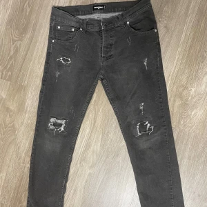 Dsquared2 - Svarta jeans från Dsquared2 med slitna detaljer och hål på både fram- och baksidan. Klassisk femficksmodell med dragkedjegylf och smal passform. Perfekta för en edgy och trendig look.