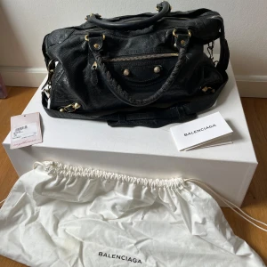 Balenciaga City Bag - Säljer min ikoniska Balenciaga Classic City bag. Inköpt via Mytheresa 2018 med ett nypris på ca 16 000kr. Väskan kommer i orginal dustbag. Fint begagnat skick. Tecken på slitage invändigt och sedan den lilla spegeln.   Pris kan diskuteras vid snabb affär.   Se serial nummer på bild nr 3 för äkthetsbevis även.