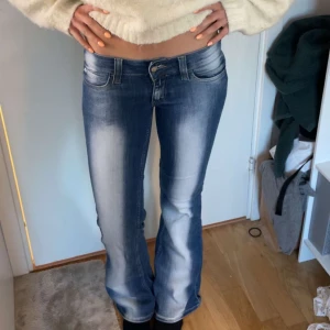 Weekday jeans - Snygga blå jeans med bootcut passform och låg midja. Jeansen har klassiska fickor fram och bak samt ljusa slitningar längs benen för en trendig look. Perfekta till vardags med en croppad topp eller hoodie.