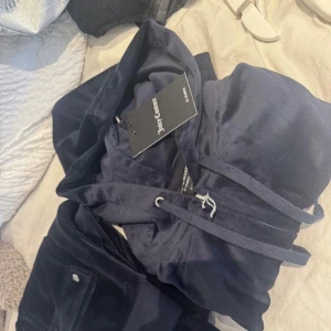 Mörkblå velourbyxor från Juicy Couture - Mysiga mörkblå velourbyxor från Juicy Couture.Använt endast en gång , helt som nya, prislapparna är av men finns kvar då jag köpte dressen nyss. Tröjan är storlek xxs men sitter som xs/s o byxorna är xs men sitter som en s också. Jag är 165 lång o dem går ner till marken för mig, då de inte kommer att komma till användning säljer jag de billigt