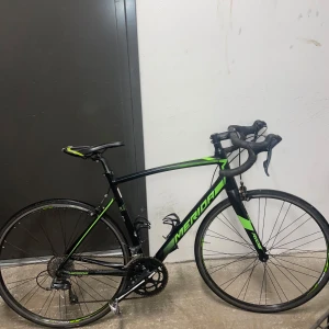Svart och grön racercykel från Merida - Säljer en snygg racercykel från Merida i svart med gröna detaljer. Cykeln har bockstyre, smala däck och lätt ram, perfekt för snabba turer på landsväg. Utrustad med växlar och flaskhållare. Passar dig som vill cykla snabbt och smidigt. Säljer den för att den tar för mycket plats och används inte längre då jag har en ny cykel. Pris går att diskutera.