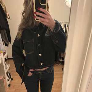 Mörkblå croppad jeansjacka/tröja  - Säljer en mörkblå croppad jeansjacka/tröja.  Jackan har en stor bröstficka och klassisk krage. Passformen är oversized och ärmarna är långa. Perfekt för dig som gillar en trendig och avslappnad stil. Perfekt till en utekväll, sommarkväll eller till vardags. Aldrig använd med prislapp kvar då jag har en liknande 