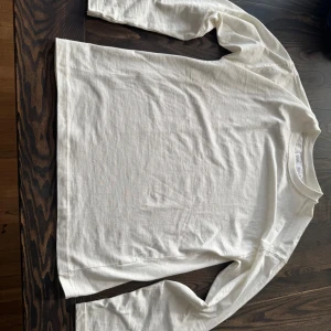 Vit långärmad tröja från Zara - Säljer en enkel och stilren vit långärmad tröja från Zara i mjuk bomull. Perfekt basplagg med rund hals och rak passform. Mycket fint skick. Skriv till mig om ni har frågor!