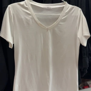 Vit v-ringad t-shirt - En klassisk vit t-shirt med v-ringning och korta ärmar. Perfekt basplagg som passar till det mesta. Enkel och stilren design utan tryck eller mönster.