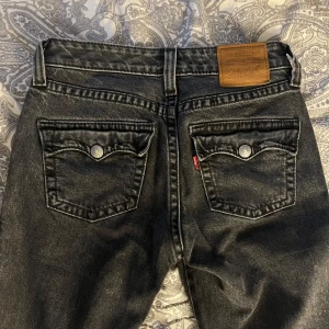 Levi's Premium Noughties Bootcut Jeans - Säljer ett par svarta Levi's Premium Noughties Bootcut jeans i tvättad svart denim. Klassisk femficksmodell med snygga detaljer på bakfickorna och bootcut passform. Limited edition. Inga defekter finns och är som nya!