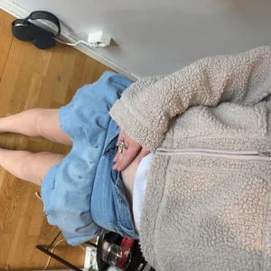 Ljusblå volangkjol i jeans - Säljer en ljusblå jeanskjol med dubbla volanger och klassiska fickor fram och bak. Kjolen har en kort passform och stängs med knapp och dragkedja. Perfekt för dig som gillar en trendig och lekfull stil. Säljer då dem är för små.