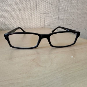 Svarta rektangulära glasögon - Stilrena svarta glasögon med rektangulära bågar. Passar dig som gillar en klassisk och enkel look. Bågarna är i plast och har en diskret design som funkar till det mesta.