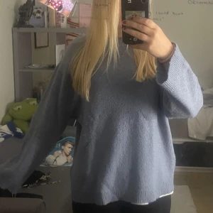 Ljusblå stickad tröja från 157 - Mysig ljusblå stickad tröja från 157 med avslappnad passform och långa ärmar. Perfekt för kyligare dagar och enkel att matcha med olika outfits. Klassisk rund halsringning och mjukt material.