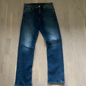 Blå Replay jeansbyxor straight fit - Säljer ett par klassiska blå jeans från Replay med raka ben . Jeansen har snygga slitningar framtill och en läderpatch med Replay-logga bak i midjan. Perfekta för dig som gillar en  enkel stil.