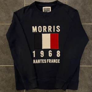 Mörkblå sweatshirt från Morris - Snygg mörkblå sweatshirt från Morris med tryck av fransk flagga och texten 'Morris 1968 Nantes France'. Tillverkad i en mjuk bomulls- och polyesterblandning. Perfekt för en avslappnad stil.
