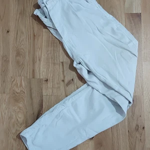Ljusbeige byxa - Säljer ett par ljusbeige chinos med resår och knapp i midjan. Byxorna har raka ben och dragkedja framtill. Perfekta för en avslappnad men ändå stilren look.