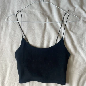 Svart croppad linnetopp från Zara - Säljer en svart croppad linnetopp från Zara med tunna axelband. Perfekt för sommaren och enkel att matcha med olika outfits. Tidlös och stilren design.