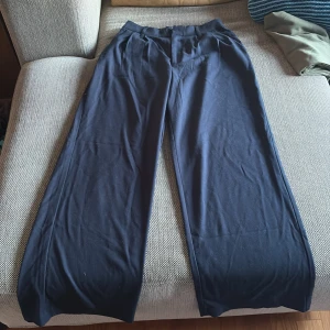 Svarta wide-leg byxor från Hollister - Säljer ett par svarta ultra high-rise wide-leg byxor från Hollister. Byxorna har hög midja, vida ben och bälteshällor. Perfekta för en avslappnad och trendig stil.