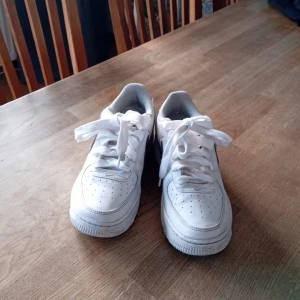 Vita Nike Air Force sneakers - Säljer ett par klassiska vita Nike Air Force sneakers. De har en rund tå och snörning framtill. Perfekta för en stilren och sportig look.