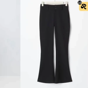 Svarta bootcut kostymbyxor - Snygga svarta kostymbyxor med bootcut-stil och hög midja. Byxorna har en klassisk design med knappar framtill och är perfekta för en stilren look.