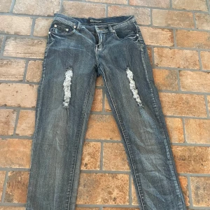 Blå jeans med slitningar från Wave Jeans - Snygga blå jeans från Wave Jeans med slitningar på framsidan och dekorativa detaljer på bakfickorna. Byxorna är väldigt bekväma och inga synliga skavanker! Hör gärna av er vid frågor.