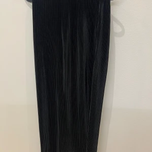 Svart plisserad kjol - Elegant svart plisserad kjol med en klassisk och tidlös design. Perfekt för att skapa en stilren look. Kjolen har en elastisk midja för extra komfort.