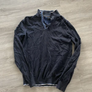 Svart tröja från Massimo Dutti - Snygg svart tröja från Massimo Dutti med en stilren v-ringning och ribbade muddar. Perfekt för en elegant och avslappnad look. Dragkedjan tyvärr sönder. Går inte att dra upp. Går säkert att laga. Strlk M men är mer som S.