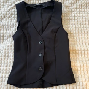 Svart väst topp - Snygg svart väst topp från gina! Strl Xs, aldrig använd, säljes pga att jag råkade köpa en för liten storlek!