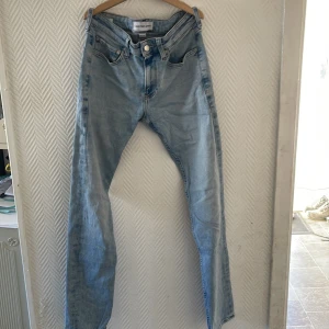 Ljusblå jeans från Calvin Klein - Snygga ljusblå jeans från Calvin Klein med klassisk femficksdesign och knappgylf. Perfekta för en avslappnad stil.