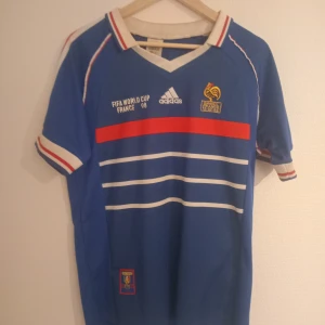 Frankriketröja 1998 - Riktigt cool retro Frankriketröja från VM 1998. Strl. M. Tröjan är i mycket bra skick och endast använd några gånger