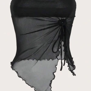 Svart tubtopp - Snygg svart tubtopp med asymmetrisk design och knytning på sidan. Toppen har en transparent look med vågiga kanter som ger en unik stil. Perfekt för en trendig outfit.