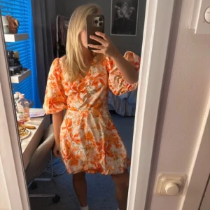 Orange blommig klänning - Säljer en färgglad och somrig klänning med blommigt mönster i orange och vitt. Från hm men slutsåld, jag har storlek M men den passar mig som har xs egentligen, aldrig använd med prislappen kvar 