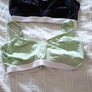 Två sportiga toppar i grönt och svart, bh - Säljer två sportiga toppar i grönt och svart med breda axelband och vit resårkant. Perfekta för träning eller en avslappnad dag. Justerbara axelband för bästa passform. Bh 