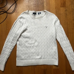 Vit stickad tröja från Gant - Säljer en stilren vit stickad tröja från Gant med kabelstickat mönster. Tröjan har långa ärmar och en rund halsringning. Är i storlek 170. Kan skicka direkt. 900 nypris 