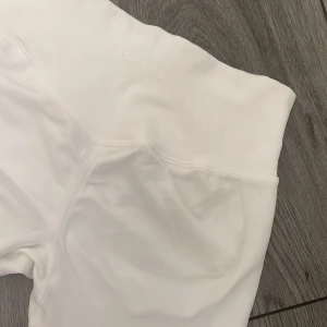 Vita tränings thights från DFYNE - Säljer ett par vita träningsthights från DFYNE. De är tillverkade i ett mjukt och stretchigt material som ger en bekväm passform. Perfekta för träning eller en avslappnad dag. 