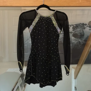 Midnight Dream Dress konståkningsklänning  - I design från Ice Fairy. Vacker dräkt i mesh som är fodrad för bästa komfort och för att ingenting ska skina igenom. Rikligt dekorerad med massor av kristaller. Dräkten är helt laddad och detta skapar en otroligt vacker, gnistrande effekt på isen. Extra kristaller följer med. Stl 16 passar 14-16 år nypris 2995kr. Helt ny. 